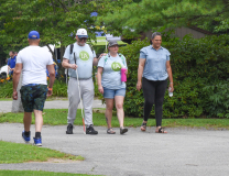 4 people walking, one with white cane